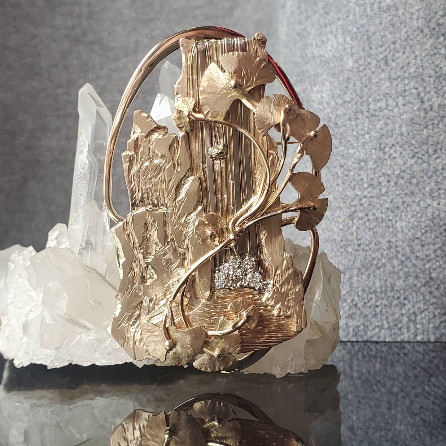 14k yellow gold Brooch featuring a cliff landscape, waterfall with pave set diamond accents and gingko branches.
