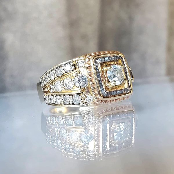 Round diamond, set in a square halo crafted from baguettes, on a wide diamond encrusted 14k yellow gold band.