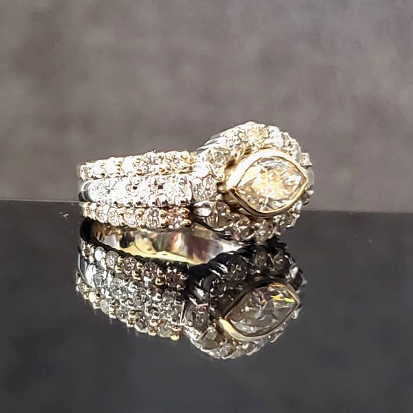Horizontal bezel set marquise with a diamond halo, on a diamond accented 14k yellow gold band.