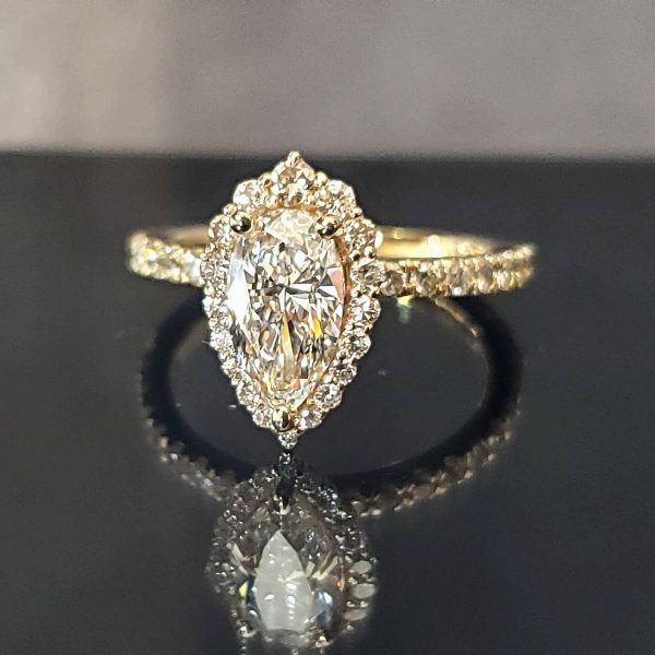 Pear shaped diamond, in an accented diamond halo with a diamond band all set in 14k yellow gold band.