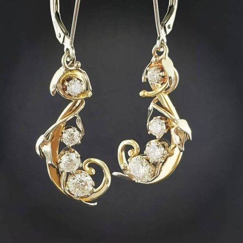 Round white diamonds prong set in leaf inspired 14k yellow gold dangle earrings.