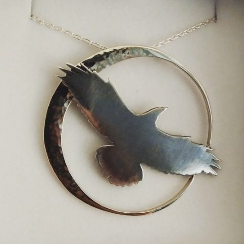 Sterling silver hand cut out Crow flies past a hammer textured white gold crescent moon slide style pendant.