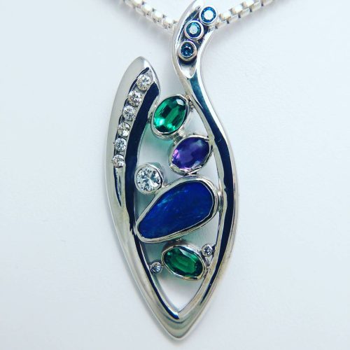 Bezel set opal, emeralds, diamonds, and amethyst in a 14k white gold open marquise shape pendant with a blue diamond bail.