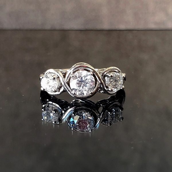 Three round brilliant diamonds in a twisted 14k white gold band with infinity designs visible from the side