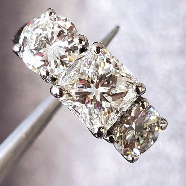 Traditional three stone style ring with a radiant center and round brilliant side diamonds set in 14k white gold