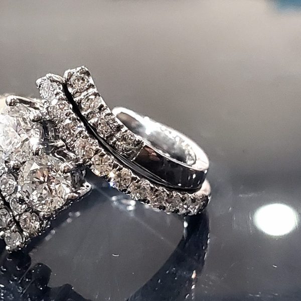 Two round diamonds are centered in this bypass ring, lined with diamonds set in 14k white gold. The center ring sits in a bypass diamond accented guard wedding band.