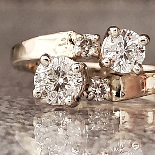 Two Round brilliant diamonds, prong set on a bypass band crafted out of 14k yellow gold with accent diamonds before the band.