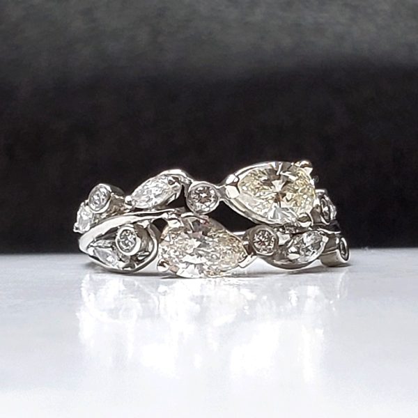 Two pear shaped diamonds, accented by smaller pear and round diamonds along the vine inspired band, crafted out of platinum, two stone engagement ring.