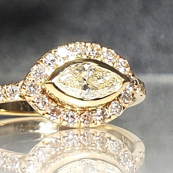 Horizontal set marquise, set in a halo with an accented diamond band, in 14k yellow gold.