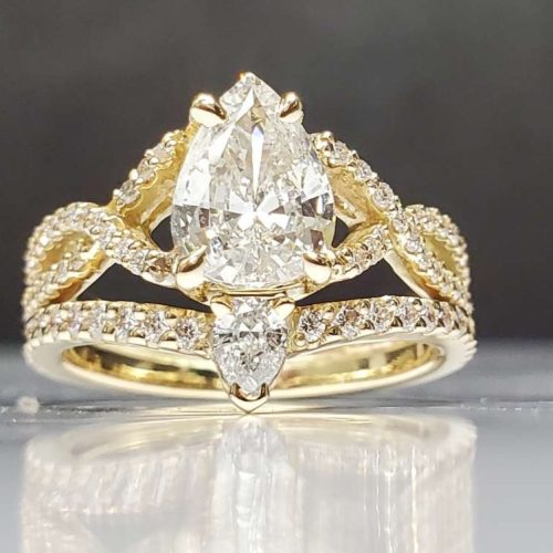 14k yellow gold infinity style diamond accented engagement ring with a claw prong set pear shape diamond. Contour diamond wedding band with pear diamond center. Created by Katherine Spencer. Made in Morgantown, West Virginia USA
