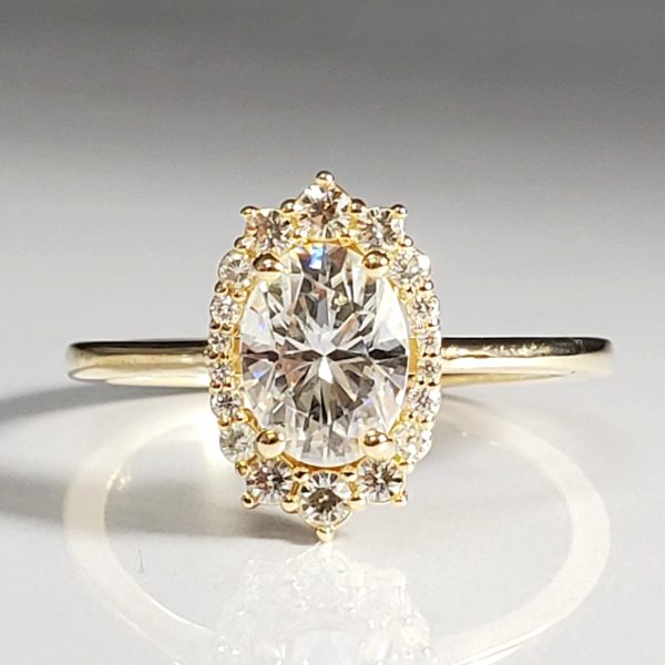Oval cut diamond with an accented diamond halo, on a dainty 14k yellow gold band.