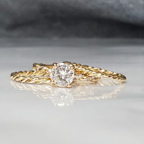 14k yellow gold diamond engagement ring and wedding band next to a mill grain edge flat satin finish wide band.