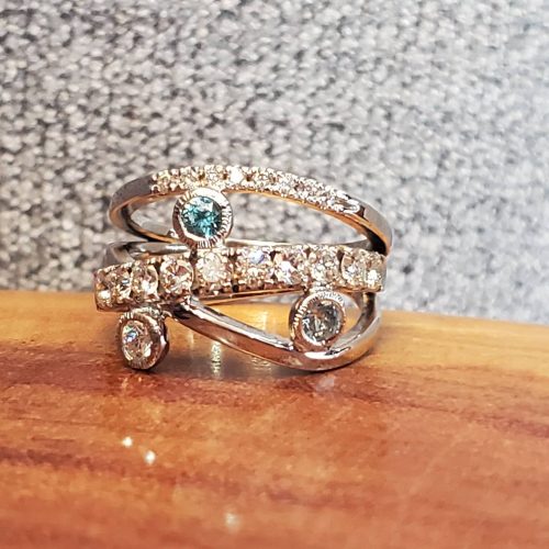 Concave 14k yellow gold band with prong set round emerald, peridot, and topaz.