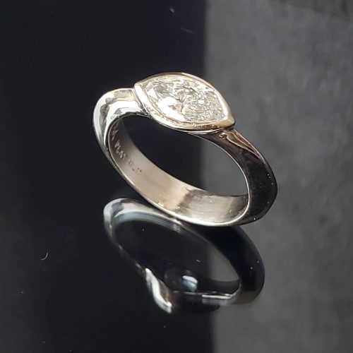 Layered wavy 14k white gold bands with a large white diamond accented with smaller bezel set gemstones.