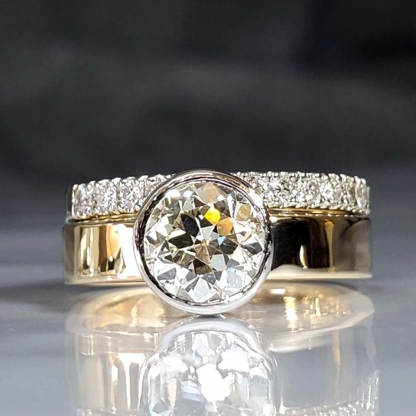 Classic, clean, simple lines. A platinum closed back bezel set diamond on a flat 14k yellow gold band. Shown with a 14 diamond French set white gold band.