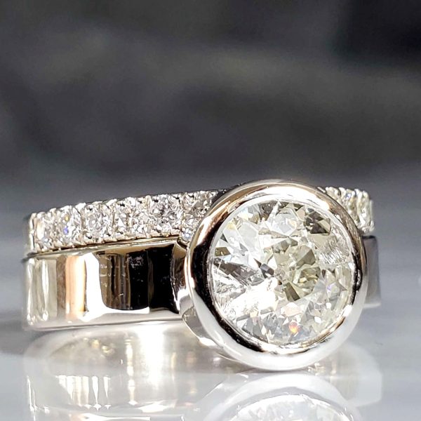 Classic, clean, simple lines. A platinum closed back bezel set diamond on a flat 14k white gold band. Shown with a 14 diamond French set white gold band.