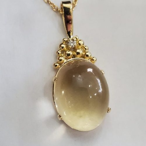 Large yellow cabochon set in a pendant with 14k yellow gold granulation details with a diamond.