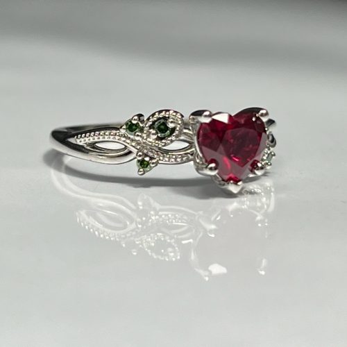 Heart shape ruby engagement ring with green diamond accents set in 18k white gold. Made in Morgantown, West Virginia USA