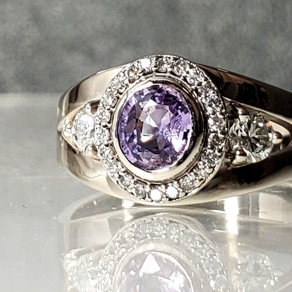 A beautiful purple sapphire set in a diamond halo with an open 14k white gold band with diamond accents.