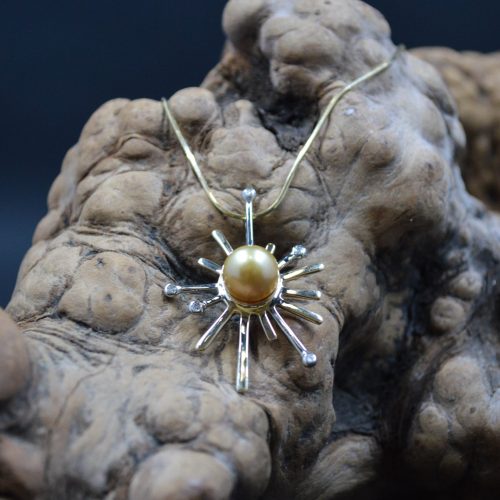 Golden yellow south sea pearl centered in a 14k white and yellow gold sunburst pendant with diamond accents.