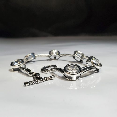 Sterling silver fancy link bracelet with alternating large round bezel set cubic zirconia with a toggle clasp.