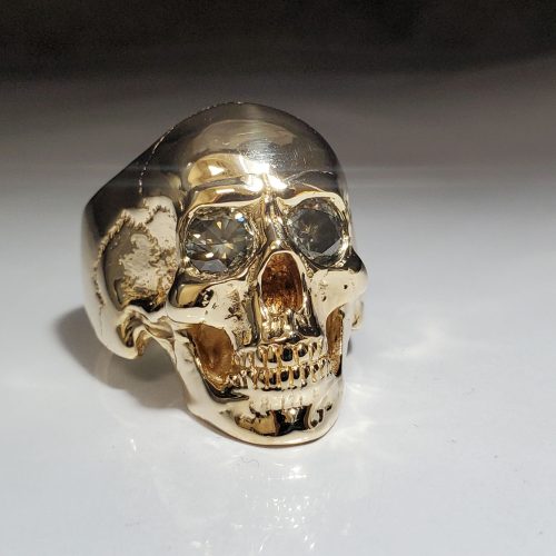 14k yellow gold realistic looking skull ring set with round smokey grey brilliant cut diamond eyes. Made in Morgantown, West Virginia USA